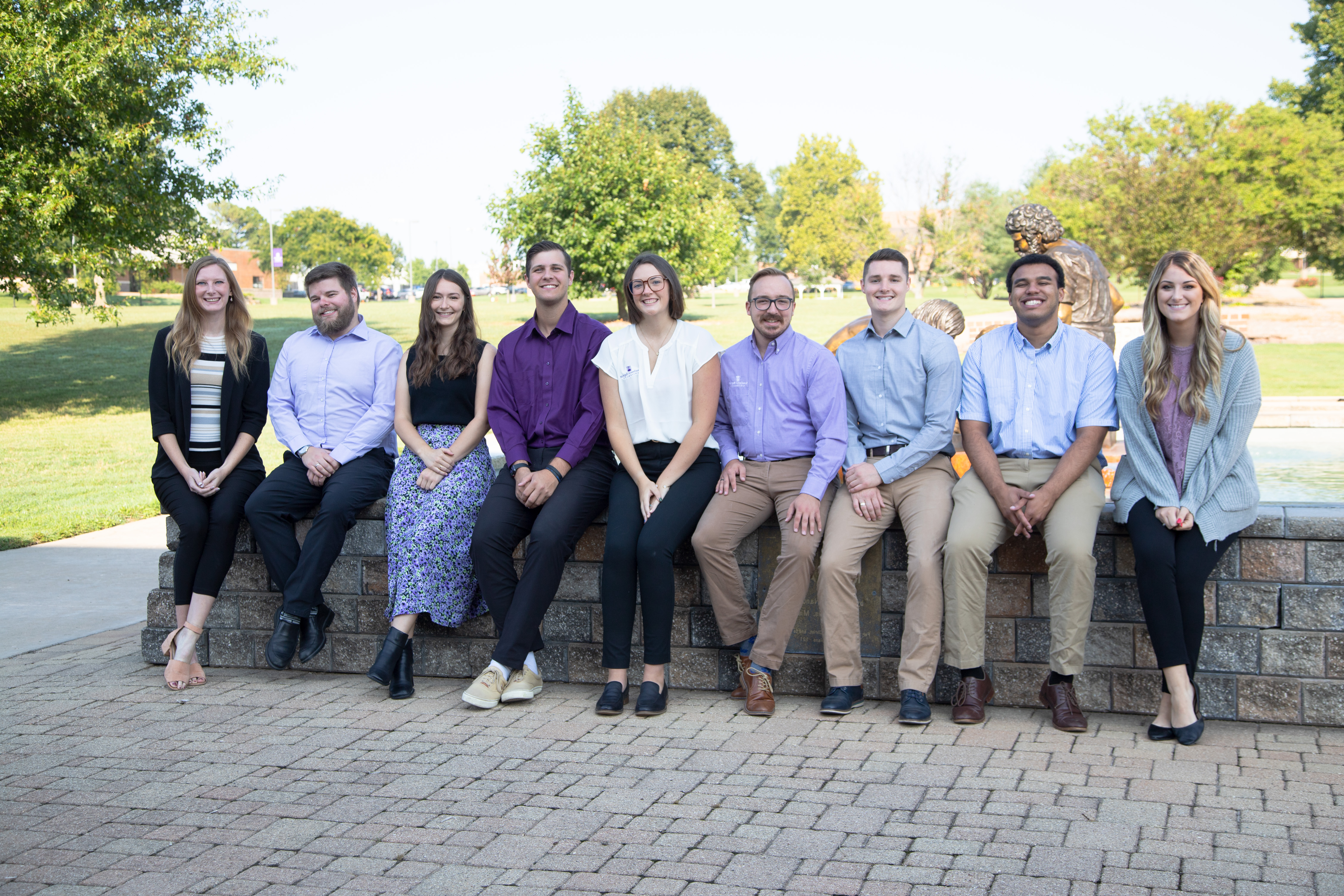 nine admissions counselors pose for picture in front of a fountain