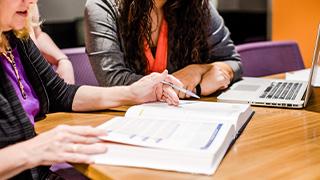 accounting professor looks at computer with student to help her with homework assignment