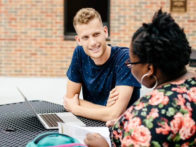 SBU students working on laptop outside